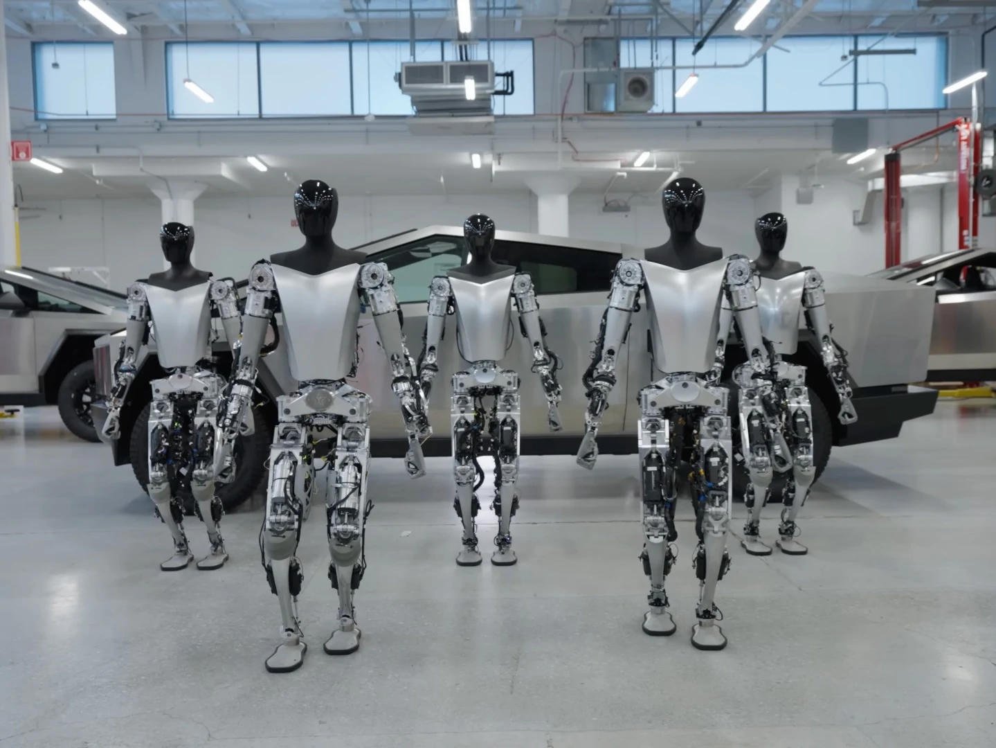 Pięć robotów Tesla Optimus w hali